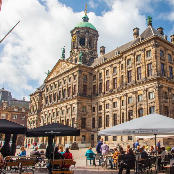 Historic Amsterdam architecture above a lively caf&eacute; terrace