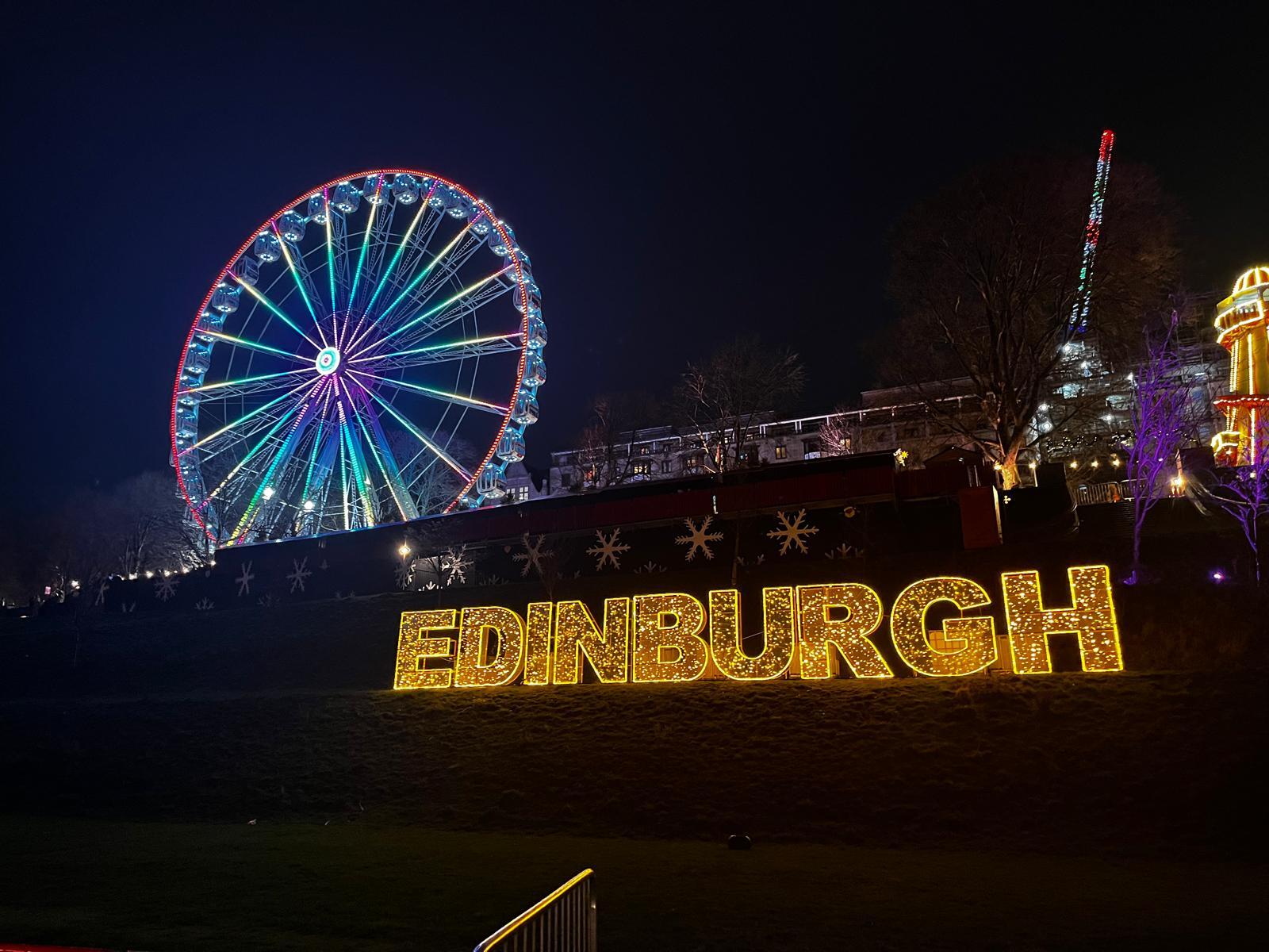 The illuminated Edinburgh sign and Ferris wheel at Edinburgh Christmas Markets